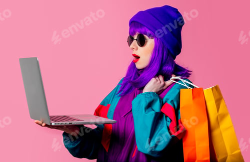 Preview: Stylish girl in 80s tracksuit hold laptop and shopping bags on pink background