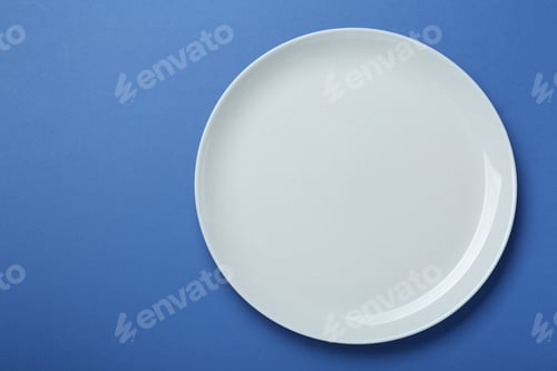 Preview: Empty white ceramic plate on blue background, top view. Space for text