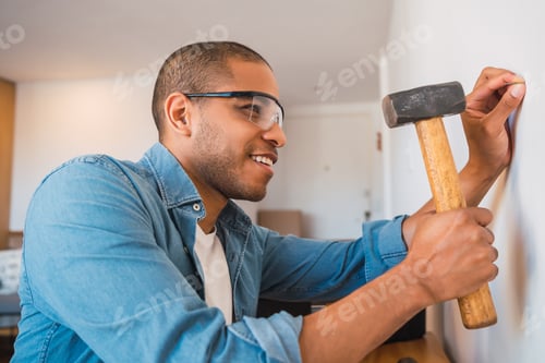 Preview: Latin man hammering nail on the wall.