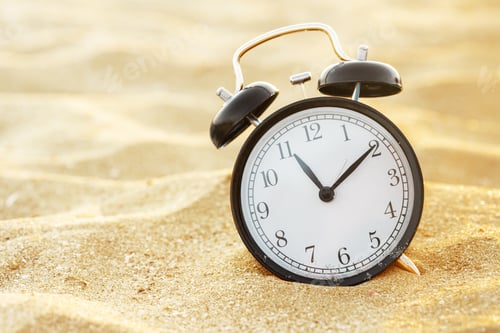 Preview: closeup of an alarm clock on the sand of a beach adjusting morning of the summer time