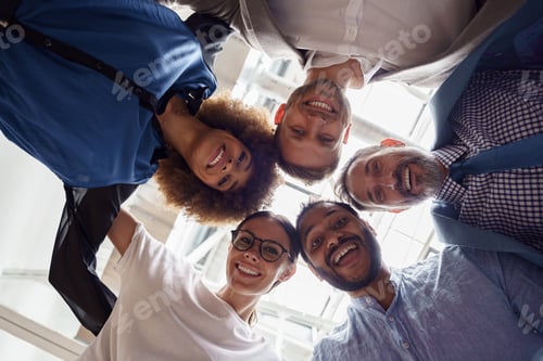 Preview: Below view of several happy business partners looking at camera while embracing each other