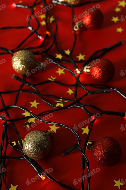 Preview: Christmas garland and balls on red background, close up