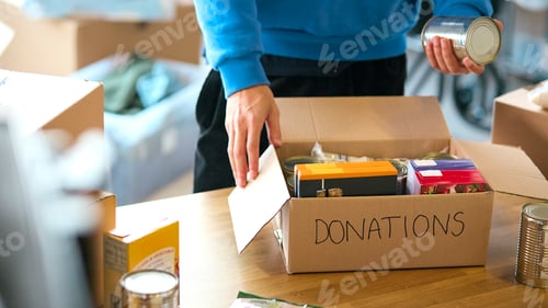 Preview: Close Up Of Male Charity Volunteer Working At Food Bank Unpacking Donations