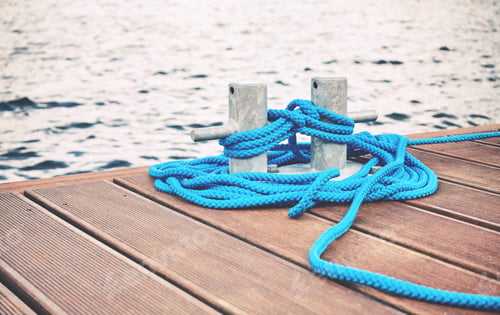 Preview: Cleat with blue rope on a wooden pier.