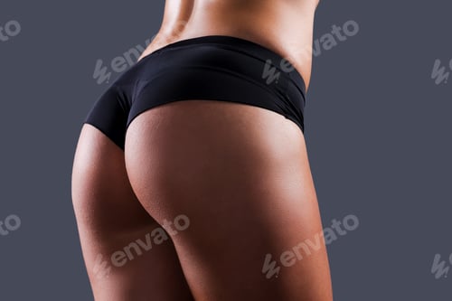 Preview: Perfect buttocks. Close-up of perfect female buttocks against grey background