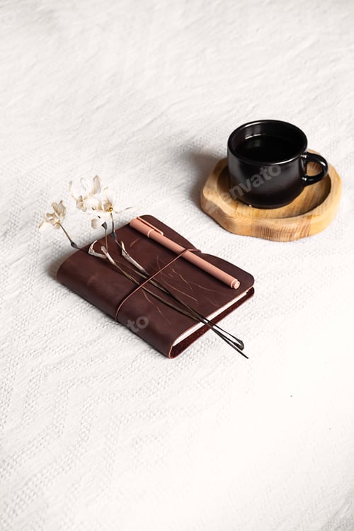 Preview: Notebook and coffee cup on the white blanket.