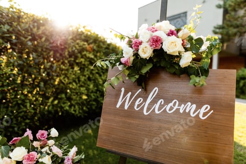 Preview: Welcome board with rose bouquet at outdoor wedding venue.