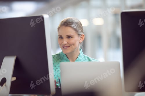 Preview: Front view of beautiful Caucasian female executive working on computer at desk in office