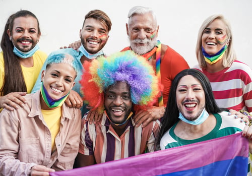 Preview: Portrait of multriacial gay people at pride parade wearing protective face mask under chin