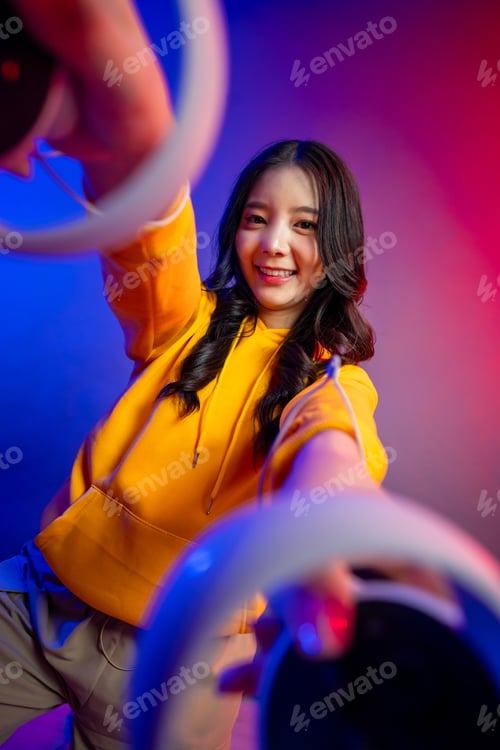 Preview: Portrait of Asian young woman gamer playing games in neon background.