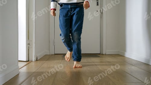 Preview: Little boy as running on a wooden floor in a long corridor at home. Happy childhood