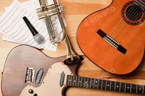 Preview: Guitars, trumpet, microphone and note sheets on wooden background, flat lay. Musical instruments