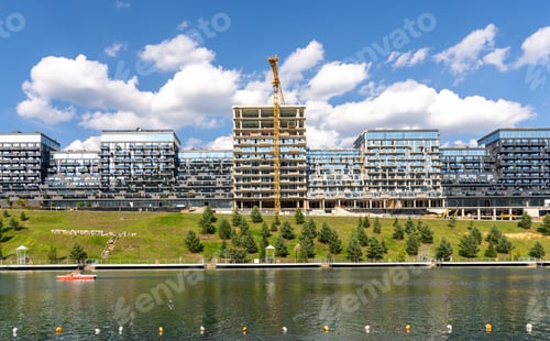 Preview: Modern residential complex near water with construction crane. Contemporary building construction.