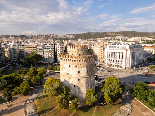 Preview: Aerial view of the White Tower in Thessaloniki, Greece, surrounded by lush greenery and the vibrant