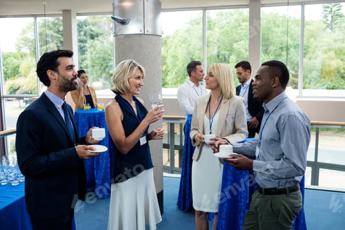 Preview: Business executives interacting with each other while having coffee