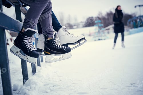 Preview: Couple wearing ice skates sitting on a guardrail