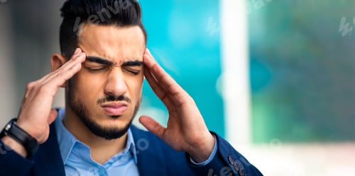 Preview: Stressed young arab businessman suffering from headache