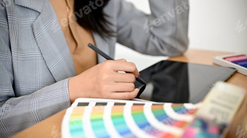 Preview: Female graphic designer working at her office desk and using digital tablet.