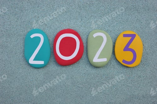 Preview: Year 2023 composed with multi colored stone numbers over green sand