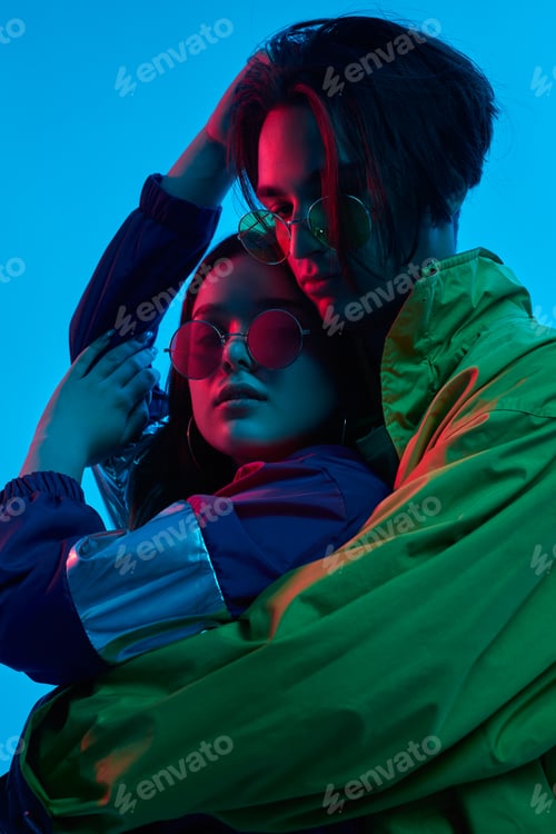 Preview: Trendy couple embracing in studio with neon illumination
