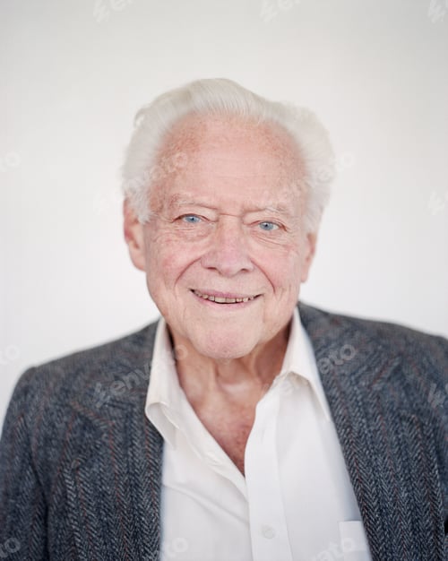 Preview: Portrait of an elderly man with grey hair in an open necked shirt, smiling.