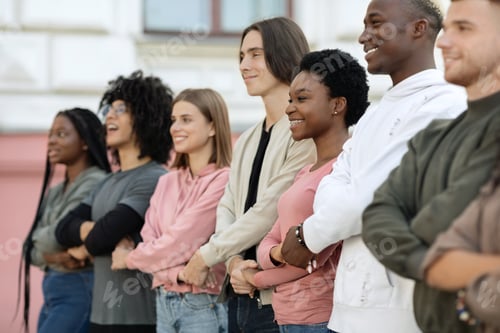 Preview: Motivated multiethnic millennials walking by street with crossed hands