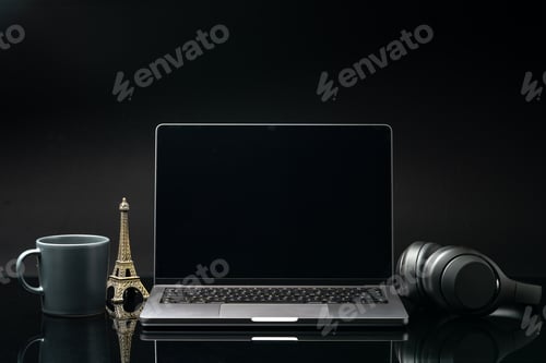 Preview: Laptop with black screen on working desk with cup and earphones on black background