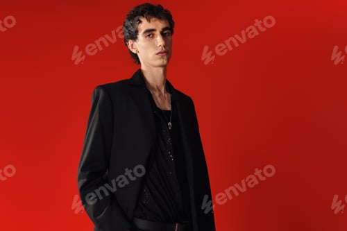 Preview: Stylish man exuding confidence in elegant black attire against a vibrant red backdrop
