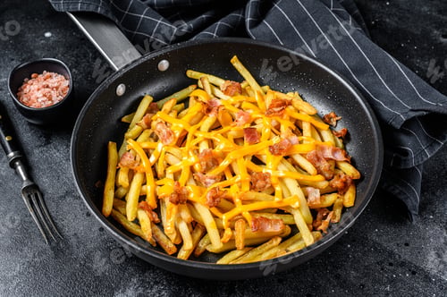 Preview: French fries baked with cheddar cheese and bacon in a pan. Black background. Top view