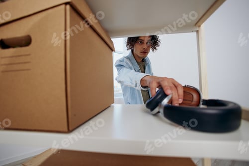 Preview: A young man unpacking things from boxes in the room sorting things out