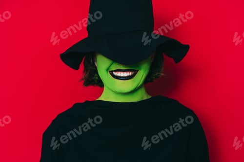 Preview: Ledy in witch costume with green skin color against red background