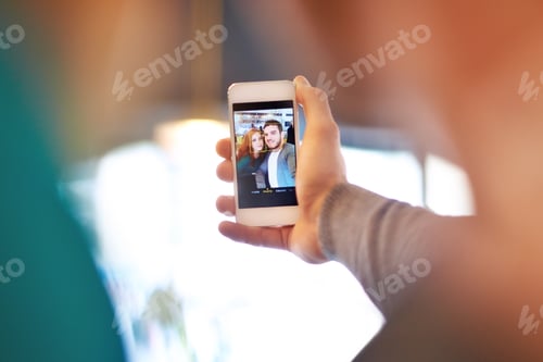 Preview: Sharing the moment. Shot of a young couple taking a photo of themselves while on a date at a cafe.