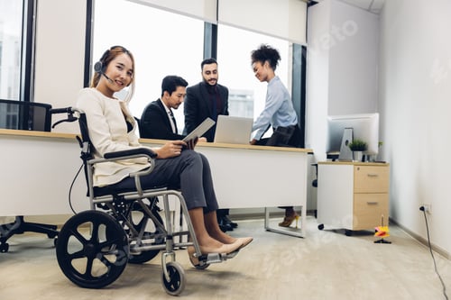 Preview: Office workers and woman on a wheelchair in bright office.