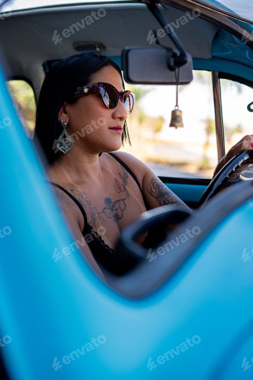 Preview: Young woman driving a vintage blue car