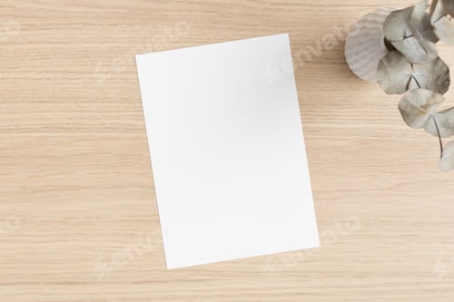 Preview: White invitation card mockup with an eucalyptus on the wooden table. 5x7 ratio, similar to A6, A5.
