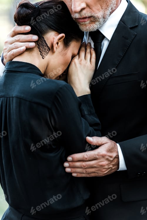 Preview: cropped view of upset senior man hugging woman on funeral