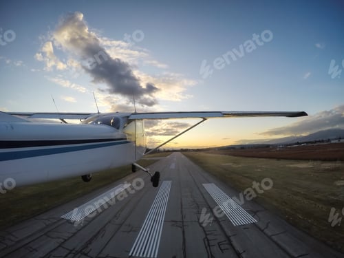 Preview: Small airplane taking off from a runway during a vibrant evening before sunset