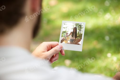 Preview: Man holding instant photo of his girlfriend, partial view
