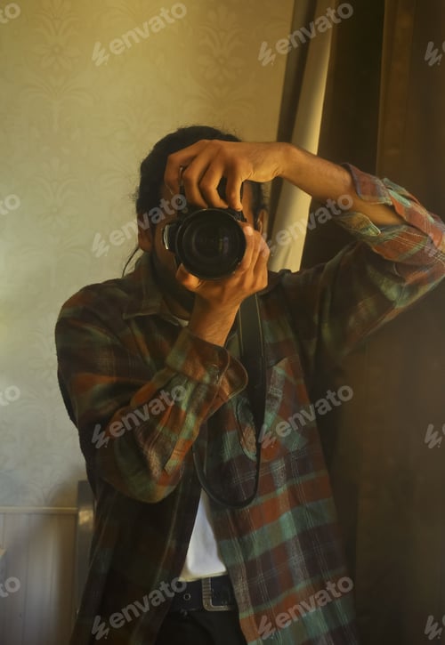 Preview: A good looking male photographer looking through the viewfinder of his DSLR camera taking selfie