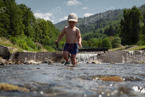 Preview: Boy plays in a clear mountain stream during his summer vacation, water fun on hot days