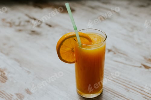 Preview: Orange juice glass with an orange slice on a wooden table, closeup shot