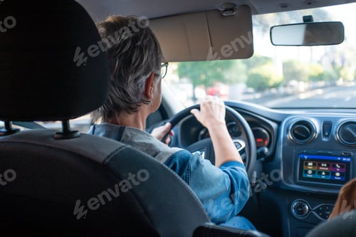 Preview: Back view of mature woman driving car in the city. Transport people concept and safety drive