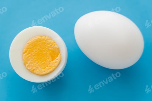 Preview: Top view of natural boiled egg with yolk on blue background