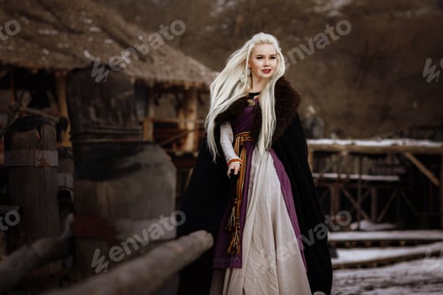 Preview: Beautiful blonde Viking dressed in a black cloak against the backdrop of the castle
