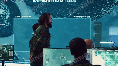 Preview: Military surveillance officers talk next to big screen in general headquarters