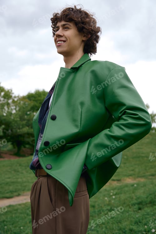 Preview: Young handsome student enjoying a peaceful walk in a green park on a cloudy day