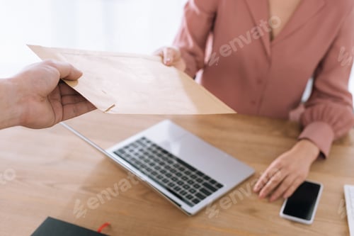 Preview: Cropped view of courier giving envelope to businesswoman at table