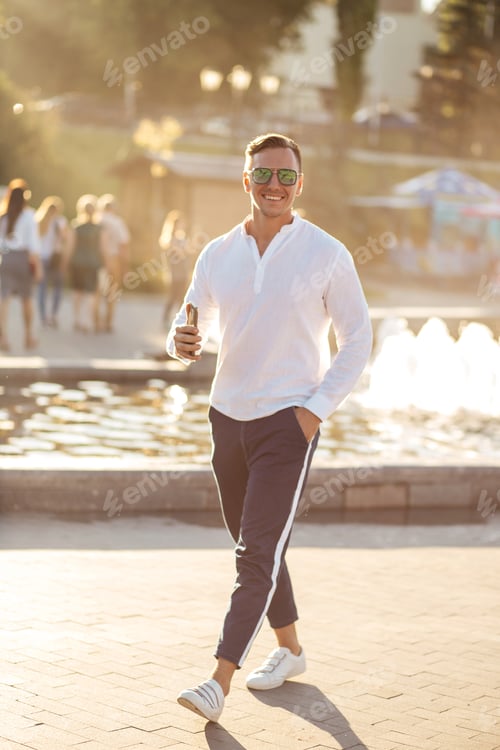 Preview: Portrait of a young confident blonde man over fountain background