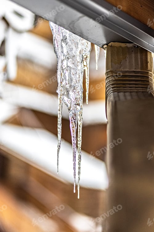 Preview: A large transparent ice icicle hangs from the roof of the house. Winter frosts
