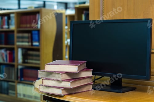 Preview: old book on the desk with computer monitor in library